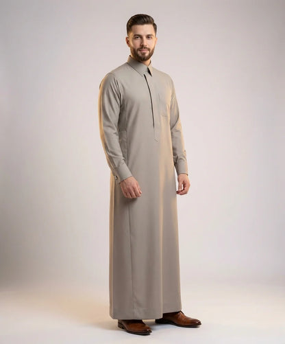 Sand Grey Executive Thobe – Refined Formal Authority by Haybah featuring a sophisticated sand grey tone, structured turn-down collar, concealed front placket, premium breathable fabric, and tailored executive fit designed for business meetings, formal gatherings, Jumuah prayers, weddings, Eid celebrations, and distinguished occasions. ثوب رمادي رملي فاخر بتصميم تنفيذي أنيق وقماش عالي الجودة يمنح الرجل حضوراً راقياً ومظهراً احترافياً في المناسبات الرسمية واليومية.