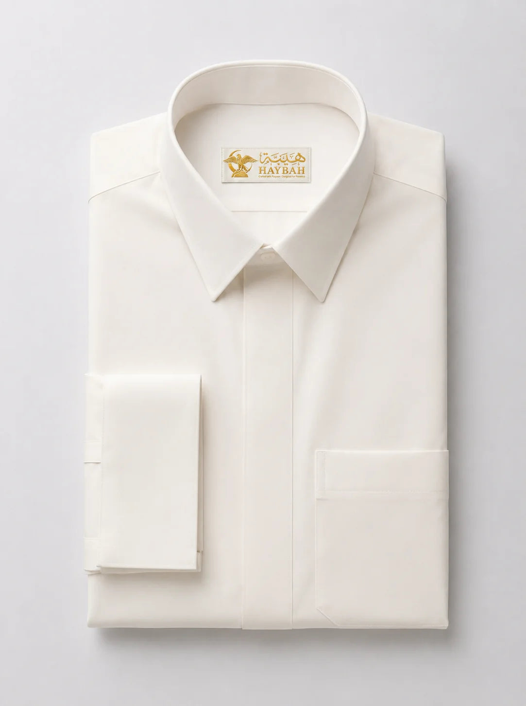 Folded Cream White Premium Formal Thobe showcasing luxury craftsmanship, elegant cream-white fabric, concealed front placket, structured formal collar, and premium finishing details by Haybah. ثوب كريمي مطوي بعناية يبرز جودة التصنيع الفاخرة والتفاصيل الدقيقة والتصميم الرسمي الأنيق المناسب للرجل العصري.