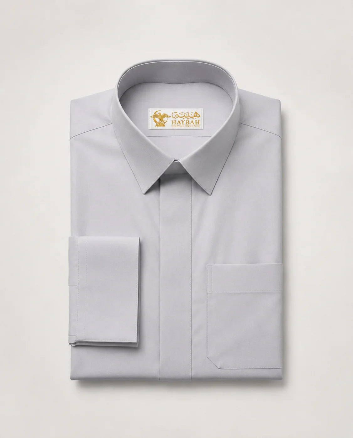Folded Light Grey Executive Thobe showcasing premium craftsmanship, elegant light grey fabric, concealed placket, structured formal collar, refined finishing details, and sophisticated executive styling by Haybah. ثوب رمادي فاتح مطوي بعناية يبرز جودة التصنيع الفاخرة والتفاصيل الدقيقة والتصميم الرسمي الأنيق للرجل العصري.