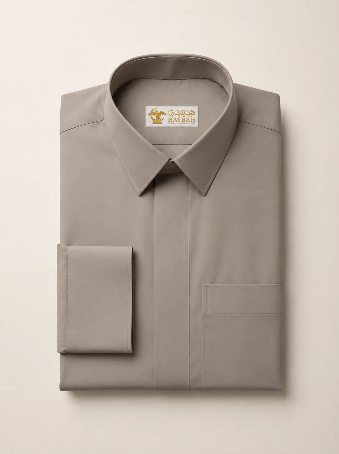 Folded Warm Grey Premium Formal Thobe showcasing premium craftsmanship, refined warm grey fabric, concealed placket, structured formal collar, precision stitching, and luxury tailoring by Haybah. ثوب رمادي دافئ مطوي بعناية يبرز جودة التصنيع الفاخرة والخياطة الدقيقة والقماش الراقي المصمم للرجل العصري الأنيق.