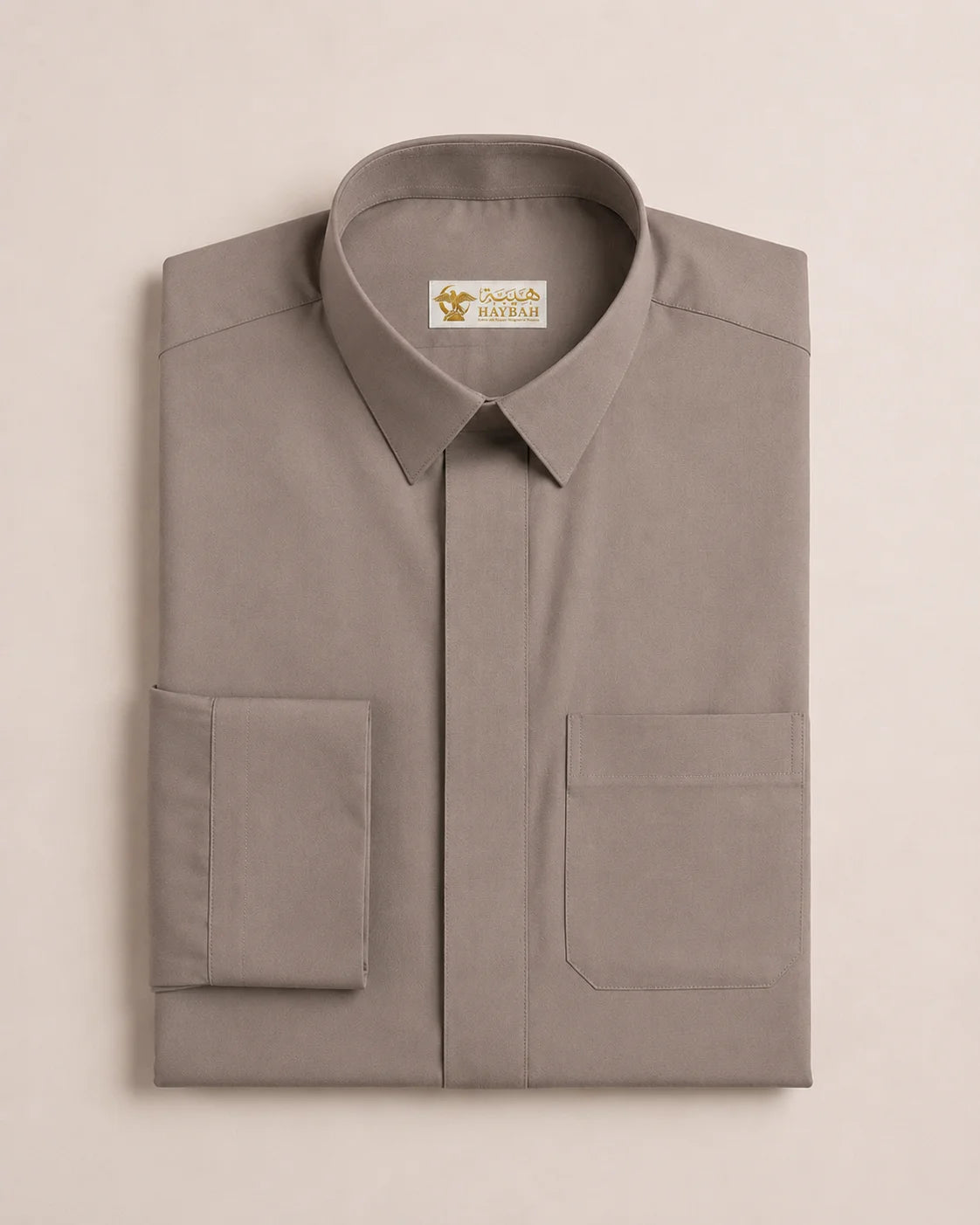 Folded Warm Grey Everyday Thobe displaying premium craftsmanship, structured collar, hidden placket, precise stitching, and breathable luxury fabric. Premium Saudi thobe, luxury jubba, men's Islamic clothing, ثوب سعودي فاخر, ثوب رجالي كلاسيكي, جلابية رجالية فاخرة, دشداشة رجالية أنيقة, ثوب يومي راقي, elegant Arab menswear suitable for Eid, Umrah travel, mosque visits, formal occasions, and modern professional lifestyles.