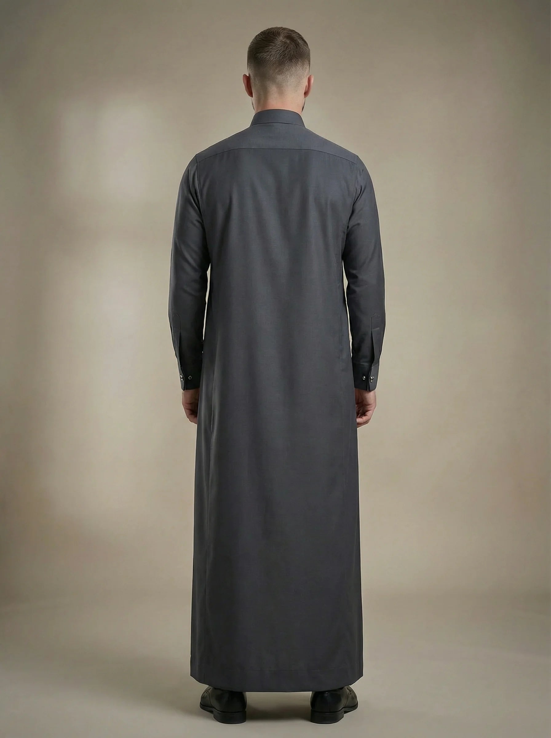 Back view of Charcoal Grey Premium Formal Thobe highlighting a clean tailored silhouette, elegant drape, premium fabric construction, and sophisticated formal menswear craftsmanship for modern gentlemen. منظر خلفي لثوب رمادي فحمي فاخر يظهر القصة المتوازنة والانسيابية الراقية والخياطة الاحترافية لمظهر أنيق ومتميز.