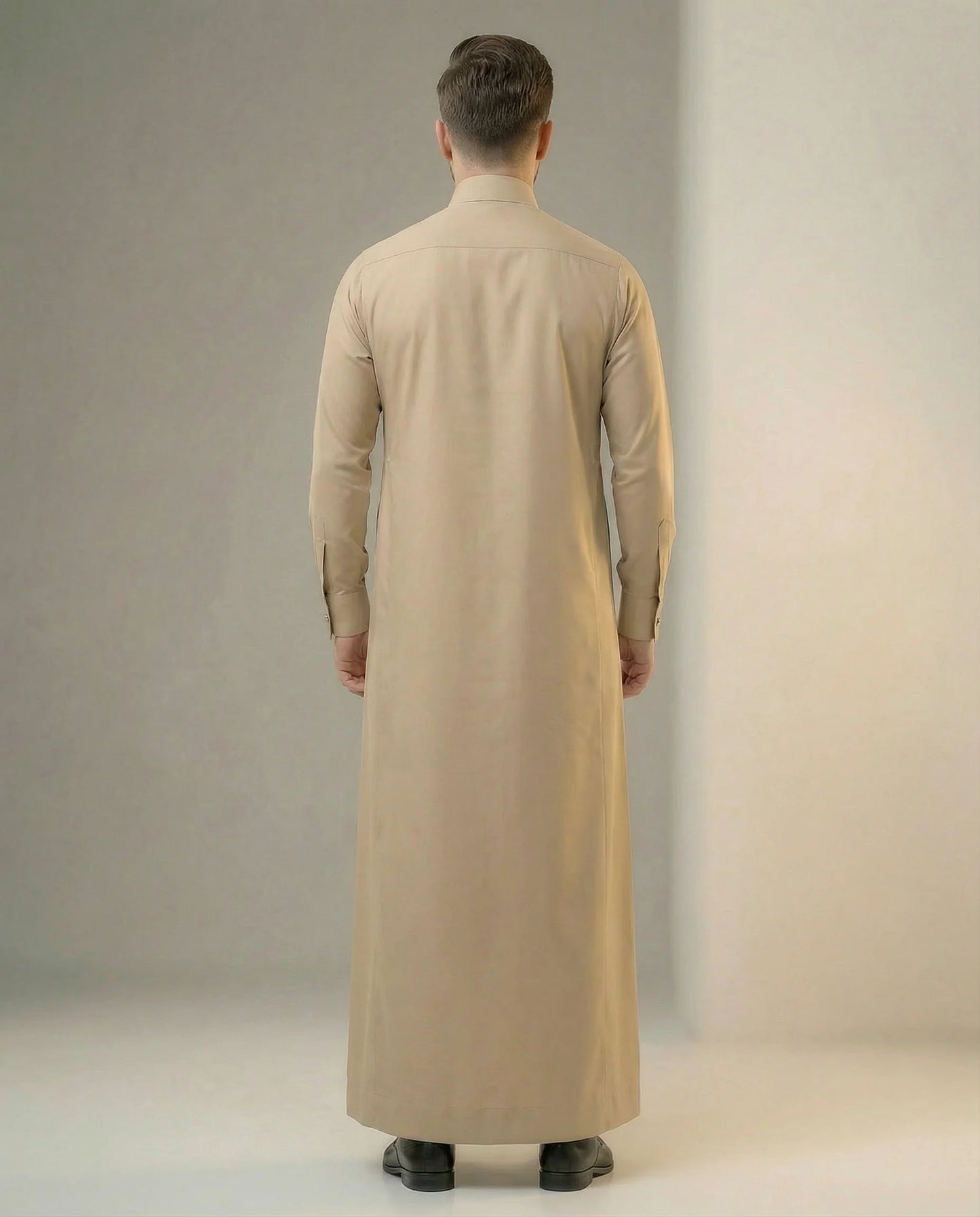 Back view of Desert Beige Executive Thobe highlighting clean tailoring, graceful fabric drape, balanced silhouette, premium craftsmanship, and refined Gulf formal wear styling for modern professionals and special occasions. منظر خلفي لثوب بيج فاخر يظهر الانسيابية الأنيقة والتفصيل الاحترافي والتصميم الراقي المناسب للمناسبات الرسمية والاحتفالات المميزة.