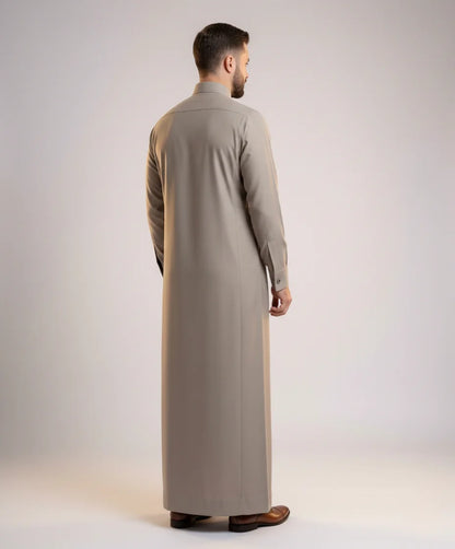 Back view of Executive Sand Grey Thobe highlighting clean tailoring, graceful fabric drape, balanced silhouette, premium construction, and sophisticated Gulf formal wear styling ideal for weddings, Eid gatherings, business events, and executive occasions. منظر خلفي لثوب رمادي رملي فاخر يظهر الانسيابية الأنيقة والتفصيل الاحترافي والمظهر الراقي المناسب للمناسبات المميزة.