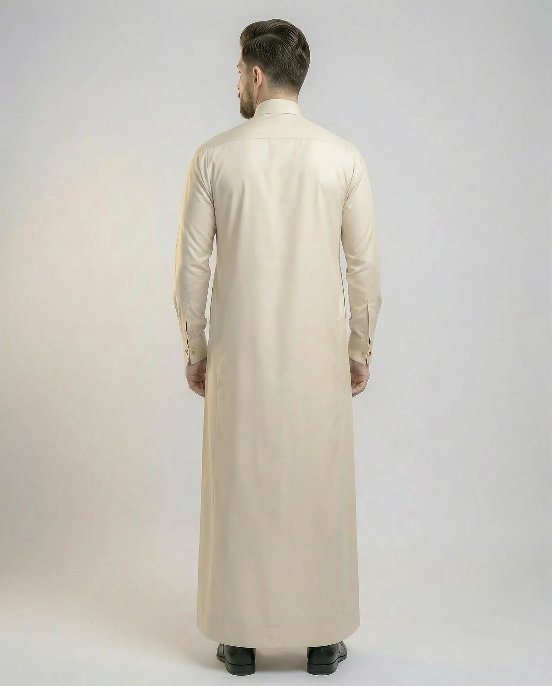 Back view of Pearl Beige Modern Formal Thobe highlighting its clean silhouette, premium fabric drape, tailored construction, and refined elegance suitable for professional and formal settings. منظر خلفي لثوب بيج لؤلؤي فاخر يظهر القصة الانسيابية والتفصيل الاحترافي والمظهر الراقي المناسب للمناسبات الرسمية.
