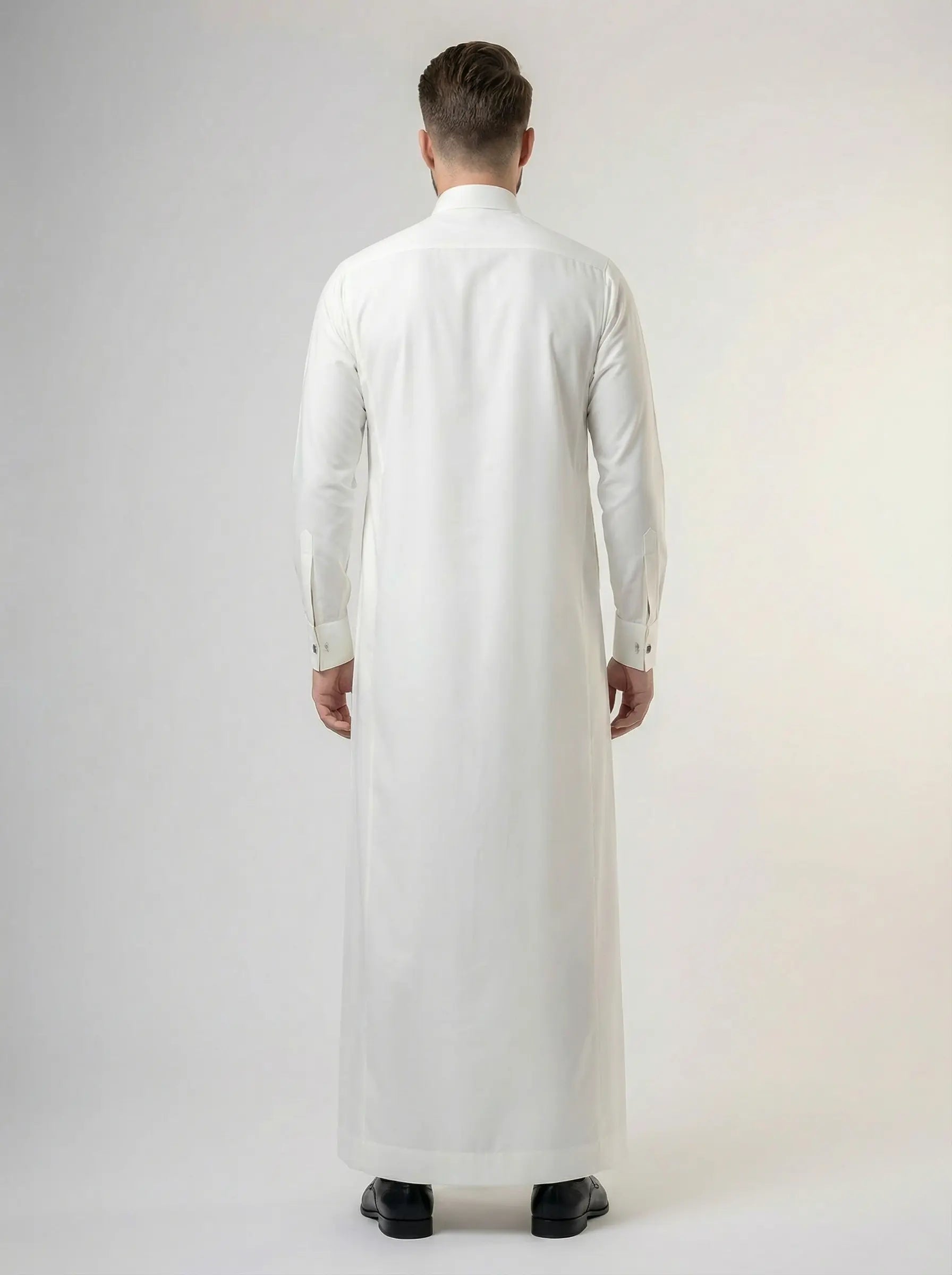 Back view of Pearl White Luxury Thobe highlighting clean tailoring, graceful fabric drape, balanced silhouette, premium construction, and sophisticated Gulf formal wear styling ideal for Eid, Jummah, weddings, nikah ceremonies, and executive occasions. منظر خلفي لثوب أبيض فاخر يظهر الانسيابية الأنيقة والتفصيل الاحترافي والمظهر الراقي المناسب للمناسبات المميزة.