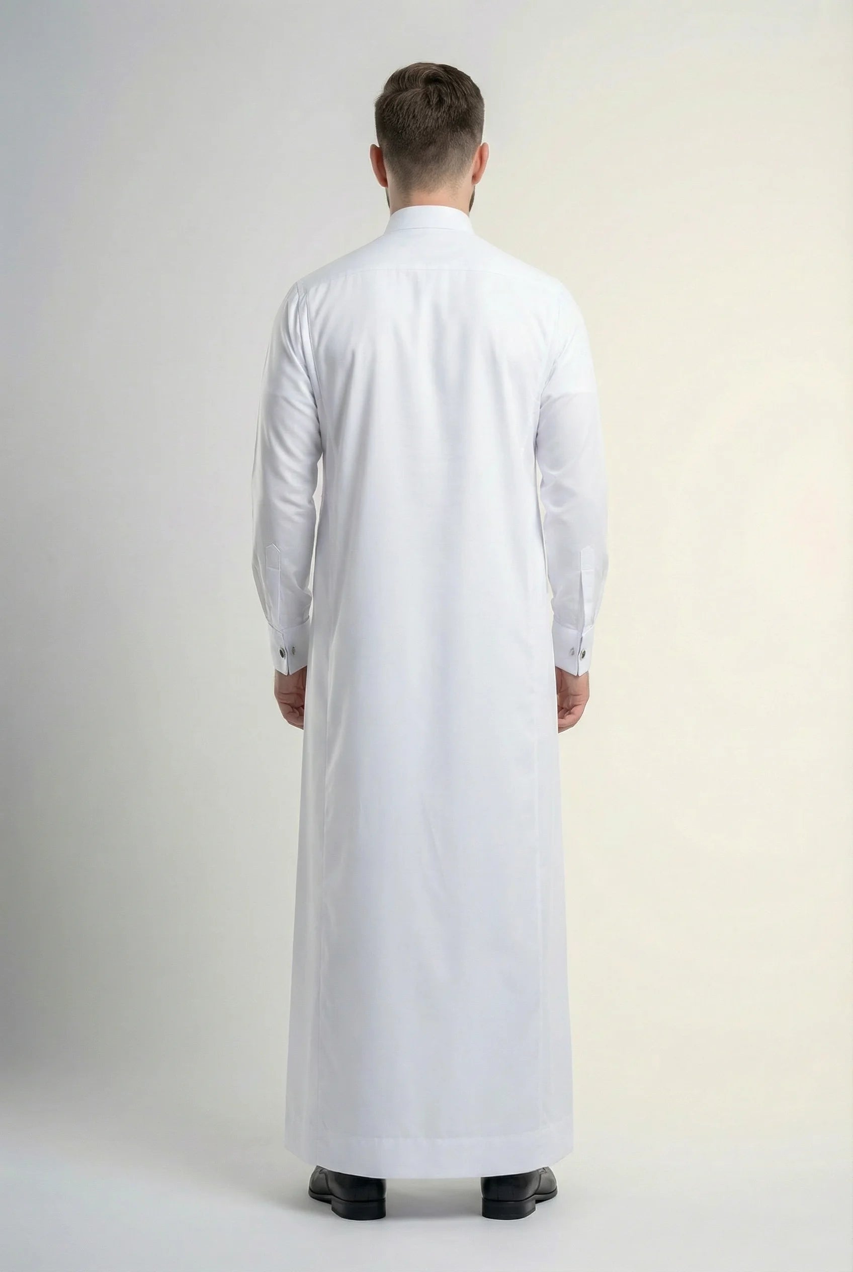 Back view of Pure White Premium Thobe highlighting a clean tailored silhouette, premium fabric drape, refined craftsmanship, and timeless formal menswear design. منظر خلفي لثوب أبيض فاخر يظهر القصة الأنيقة والانسيابية المثالية والتفصيل الاحترافي لمظهر راقٍ ومتوازن.