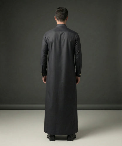 Back view of Smoke Black Premium Thobe highlighting its clean tailored construction, balanced silhouette, smooth fabric drape, premium craftsmanship, and sophisticated formal appearance designed for modern gentlemen. منظر خلفي لثوب أسود دخاني فاخر يظهر القصة المتقنة والانسيابية الراقية والتفاصيل الأنيقة المناسبة للبيئات المهنية والمناسبات الرسمية.