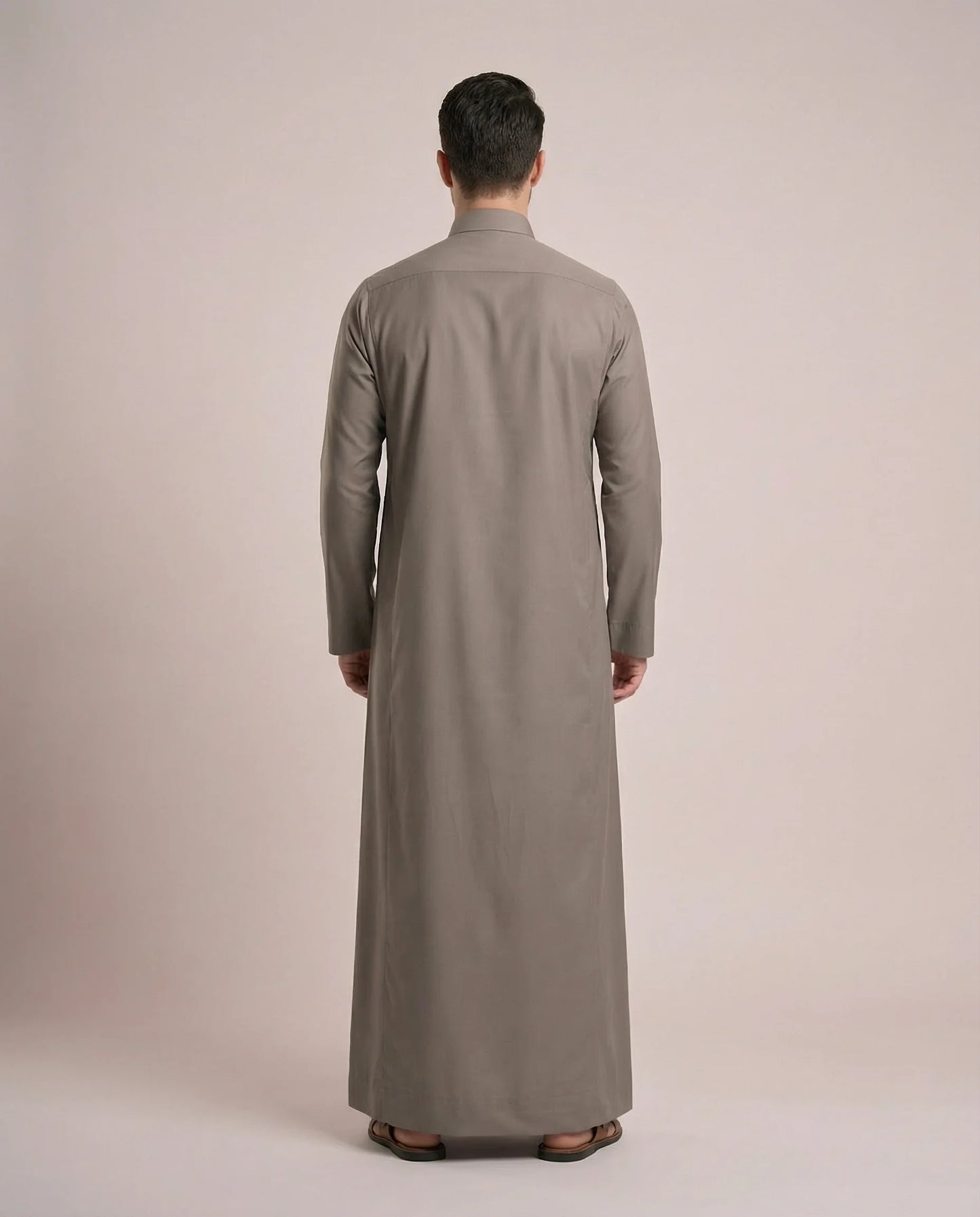 Back view of Warm Grey Everyday Thobe Contemporary Classic showcasing clean tailoring, full-length modest silhouette, balanced proportions, and premium fabric drape. Men's Saudi thobe, luxury Arabic clothing, premium jubba, ثوب رجالي سعودي, ثوب رسمي رجالي, جلابية رجالية طويلة, ملابس إسلامية رجالية فاخرة, modern Islamic fashion combining traditional elegance, comfort, professionalism, and timeless Middle Eastern style.