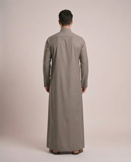 Back view of Warm Grey Everyday Thobe Contemporary Classic showcasing clean tailoring, full-length modest silhouette, balanced proportions, and premium fabric drape. Men's Saudi thobe, luxury Arabic clothing, premium jubba, ثوب رجالي سعودي, ثوب رسمي رجالي, جلابية رجالية طويلة, ملابس إسلامية رجالية فاخرة, modern Islamic fashion combining traditional elegance, comfort, professionalism, and timeless Middle Eastern style.