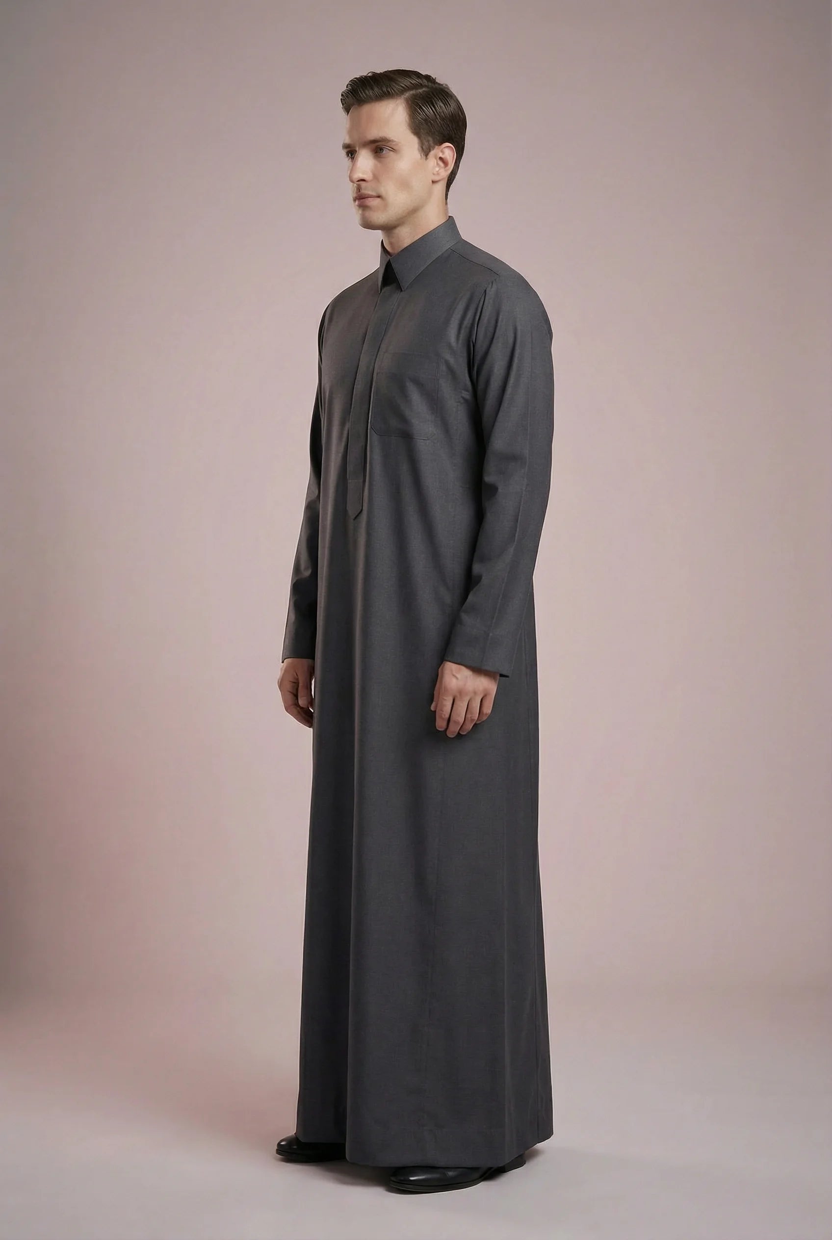 Side profile of Charcoal Grey Executive Saudi Thobe displaying a streamlined silhouette, tailored construction, structured turn-down collar, and premium charcoal fabric. Luxury men's jubba, Saudi thobe for men, traditional Islamic clothing, ثوب سعودي أنيق, ثوب رجالي فاخر, دشداشة رجالية رسمية, جلابية رجالية مودرن, elegant modest wear crafted for business meetings, special events, and everyday sophistication.