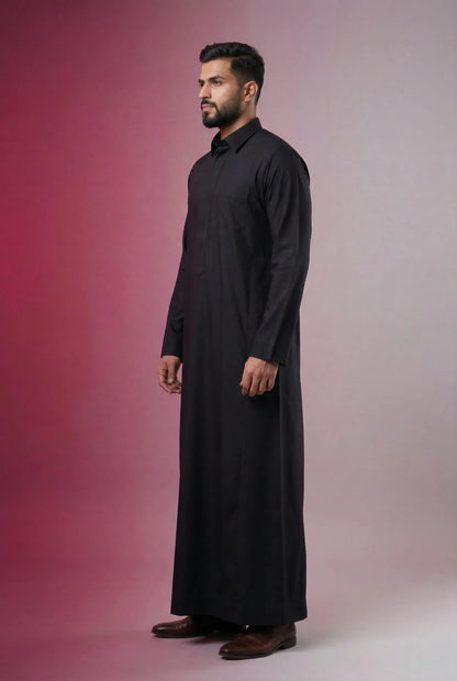 Deep Black Classic Thobe side profile showcasing structured tailoring, premium breathable fabric, concealed placket, and executive Saudi-inspired design. Luxury men's thobe, premium Saudi jubba, Islamic menswear, ثوب أسود أنيق, ثوب رجالي فاخر, ثوب سعودي مودرن, جلابية رجالية راقية, دشداشة رجالية حديثة, modest fashion designed for business professionals and formal occasions.