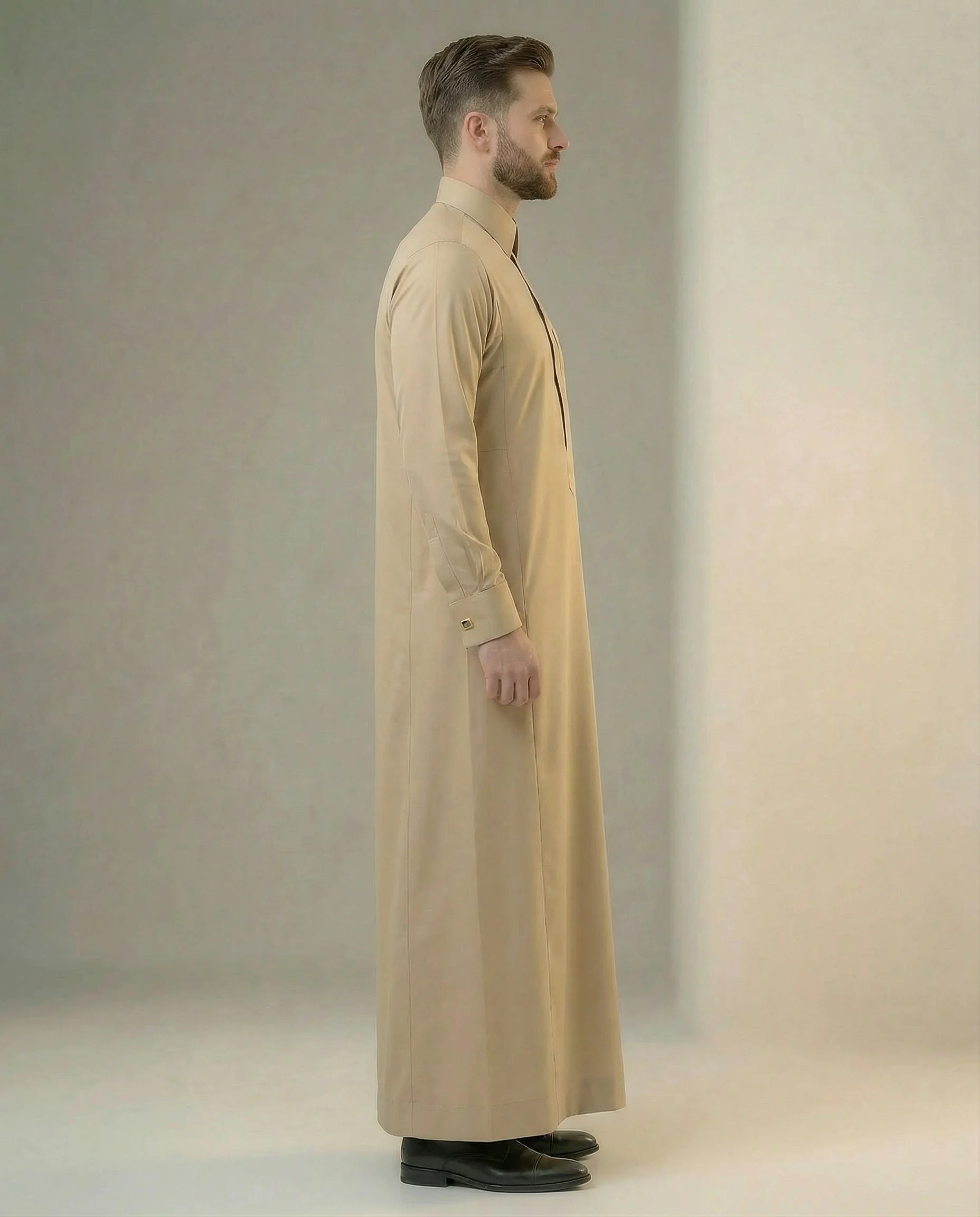Side profile of Desert Beige Executive Thobe featuring a streamlined silhouette, concealed placket, structured collar, executive tailoring, premium comfort, and timeless Gulf elegance crafted for formal gatherings, weddings, business events, and luxury occasion wear. منظر جانبي لثوب بيج فاخر يبرز القصة الأنيقة والتفاصيل الدقيقة والمظهر التنفيذي الراقي للرجل العصري.