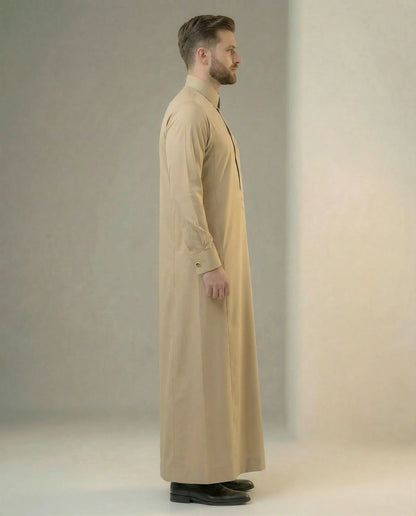Side profile of Desert Beige Executive Thobe featuring a streamlined silhouette, concealed placket, structured collar, executive tailoring, premium comfort, and timeless Gulf elegance crafted for formal gatherings, weddings, business events, and luxury occasion wear. منظر جانبي لثوب بيج فاخر يبرز القصة الأنيقة والتفاصيل الدقيقة والمظهر التنفيذي الراقي للرجل العصري.