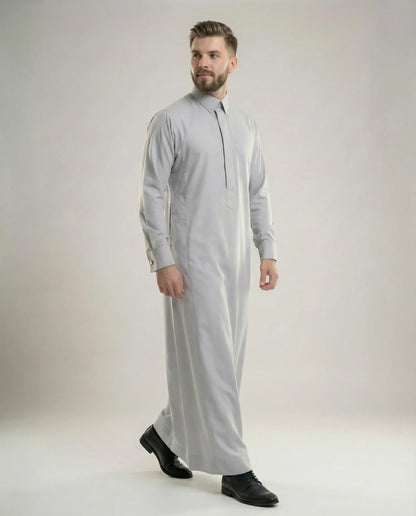 Walking view of Light Grey Executive Thobe featuring timeless elegance, premium breathable fabric, concealed placket, structured collar, and modern executive styling for confident professional wear. إطلالة أثناء المشي لثوب رمادي فاتح فاخر تبرز الأناقة العصرية والخياطة المتقنة والراحة المثالية للرجل الأنيق.