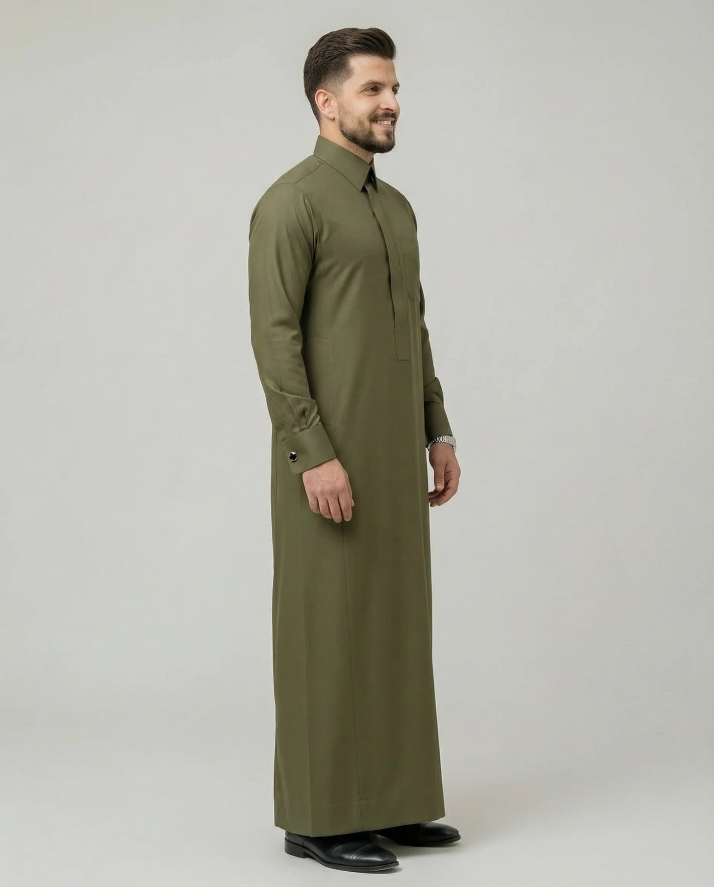 Side profile of Olive Green Premium Formal Thobe featuring a streamlined silhouette, structured collar, concealed placket, luxury tailoring, and sophisticated modern Gulf fashion styling with exceptional comfort and elegance. منظر جانبي لثوب أخضر زيتوني فاخر يبرز الأناقة العصرية والتفصيل الدقيق والانسيابية المثالية للرجل الأنيق.
