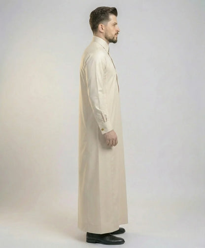 Side profile view of Pearl Beige Modern Formal Thobe featuring a streamlined fit, concealed front placket, premium tailoring, structured collar, and sophisticated modern Gulf fashion styling. منظر جانبي لثوب بيج لؤلؤي فاخر يبرز الأناقة العصرية والتفصيل الدقيق والانسيابية المثالية للرجل الأنيق.