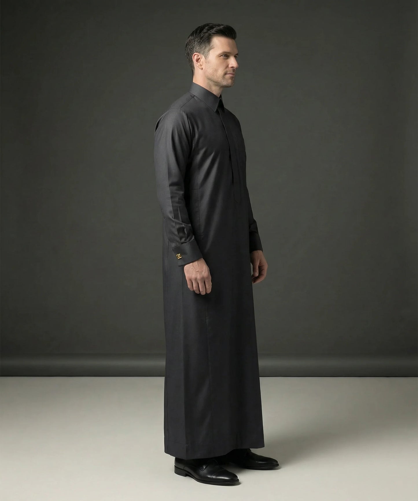 Side profile of Smoke Black Executive Thobe featuring a streamlined silhouette, concealed placket, luxury tailoring, premium comfort, structured collar, and sophisticated Gulf fashion designed for formal events, weddings, Eid celebrations, executive occasions, and luxury menswear. منظر جانبي لثوب أسود دخاني فاخر يبرز القصة الأنيقة والفخامة الخليجية والتفاصيل الدقيقة.