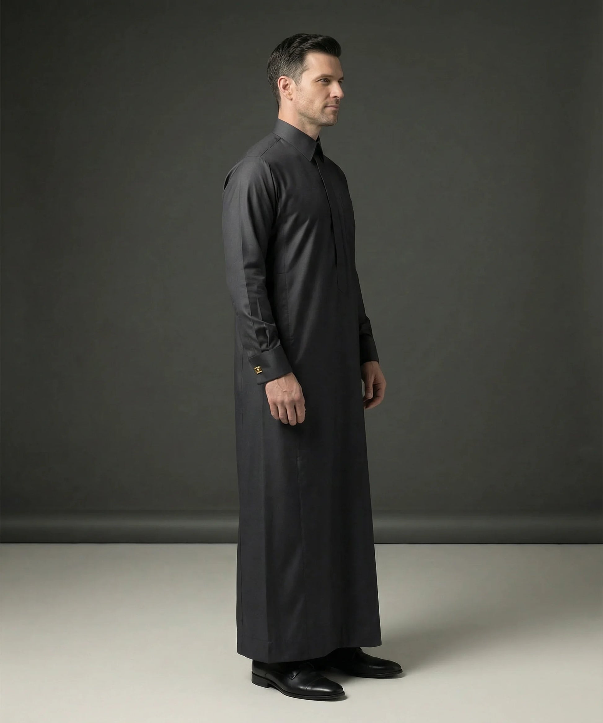Side profile of Smoke Black Executive Thobe featuring a streamlined silhouette, concealed placket, luxury tailoring, premium comfort, structured collar, and sophisticated Gulf fashion designed for formal events, weddings, Eid celebrations, executive occasions, and luxury menswear. منظر جانبي لثوب أسود دخاني فاخر يبرز القصة الأنيقة والفخامة الخليجية والتفاصيل الدقيقة.