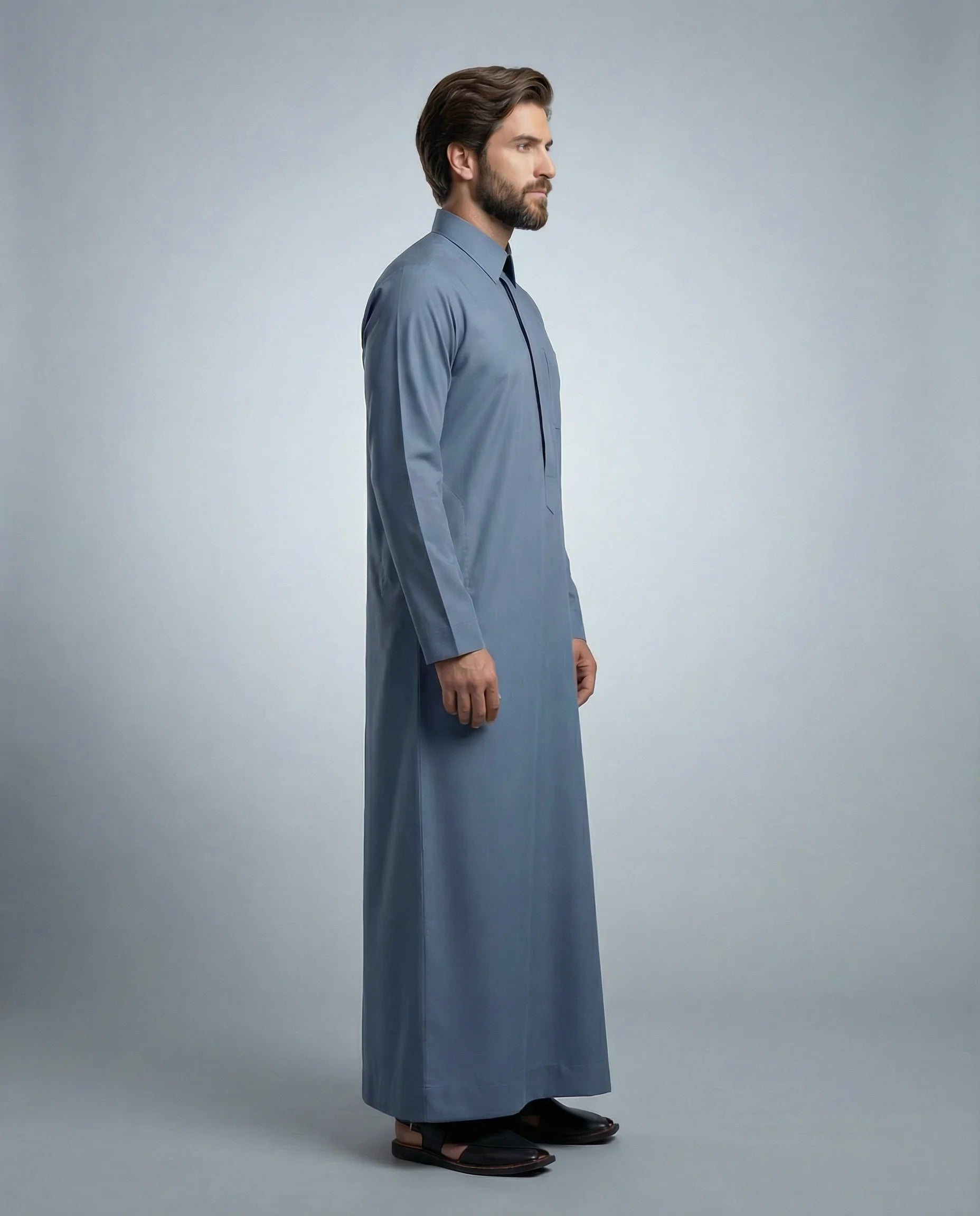 Side profile of Steel Blue Classic Everyday Thobe displaying modern tailoring, streamlined silhouette, structured collar, and lightweight breathable fabric. Luxury men's thobe, Saudi jubba, Arabic clothing, ثوب سعودي أنيق, ثوب رجالي فاخر, ثوب أزرق فولاذي, دشداشة رجالية رسمية, جلابية رجالية مودرن, premium Islamic menswear crafted for office wear, Ramadan gatherings, Eid celebrations, and sophisticated daily use.