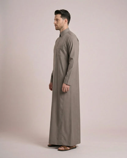 Side profile of Warm Grey Everyday Saudi Thobe highlighting streamlined tailoring, structured turn-down collar, clean silhouette, and sophisticated warm grey tone. Luxury men's thobe, Saudi jubba, Arabic clothing, ثوب سعودي أنيق, ثوب رجالي فاخر, دشداشة رجالية رسمية, جلابية رجالية مودرن, premium modest wear crafted for office professionals, family gatherings, Eid events, Ramadan evenings, and distinguished everyday elegance.