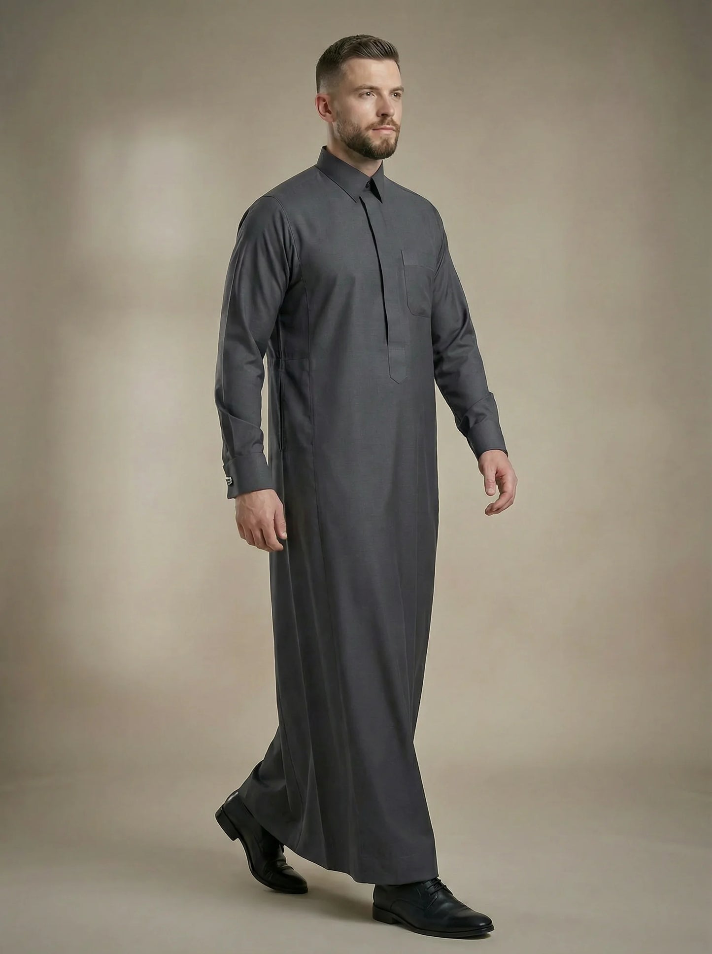 Walking view of Charcoal Grey Signature Thobe displaying premium craftsmanship, refined structure, concealed placket design, luxury fabric, and distinguished Gulf fashion style. Suitable for executive meetings, weddings, formal receptions, and sophisticated celebrations. إطلالة أثناء الحركة لثوب رمادي فحمي فاخر يعكس الفخامة الخليجية والتصميم الأنيق للمناسبات الرسمية.