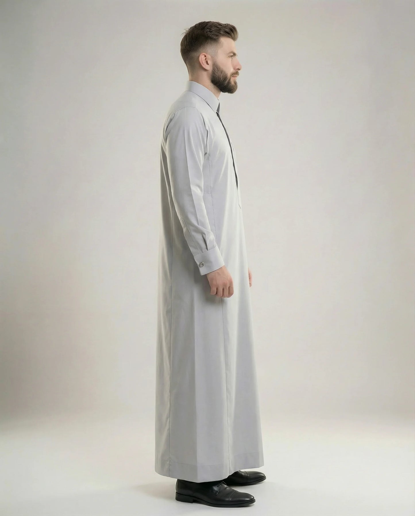 Side profile of Light Grey Luxury Thobe showcasing elegant proportions, premium fabric, concealed placket design, executive sophistication, and modern Gulf styling ideal for formal meetings, business gatherings, weddings, and ceremonial occasions. منظر جانبي لثوب رمادي فاتح فاخر يبرز القصة الأنيقة والتفصيل الراقي للمناسبات التنفيذية والرسمية.