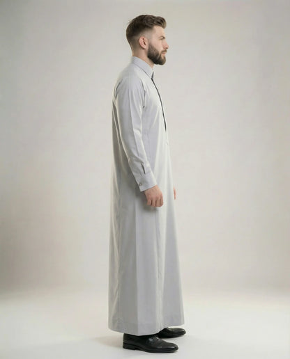 Side profile of Light Grey Luxury Thobe showcasing elegant proportions, premium fabric, concealed placket design, executive sophistication, and modern Gulf styling ideal for formal meetings, business gatherings, weddings, and ceremonial occasions. منظر جانبي لثوب رمادي فاتح فاخر يبرز القصة الأنيقة والتفصيل الراقي للمناسبات التنفيذية والرسمية.