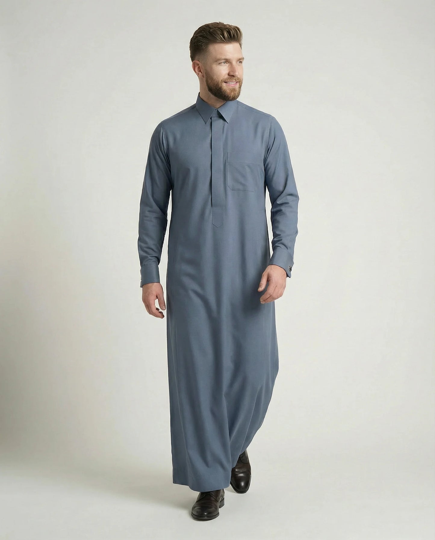 Walking view of Slate Blue Luxury Thobe displaying refined movement, premium craftsmanship, luxury fabric, concealed placket styling, and sophisticated Gulf fashion appeal. Suitable for formal events, business occasions, weddings, and prestigious celebrations. إطلالة أثناء الحركة لثوب أزرق رمادي فاخر يجسد الفخامة الخليجية والتصميم الأنيق للمناسبات الرسمية.