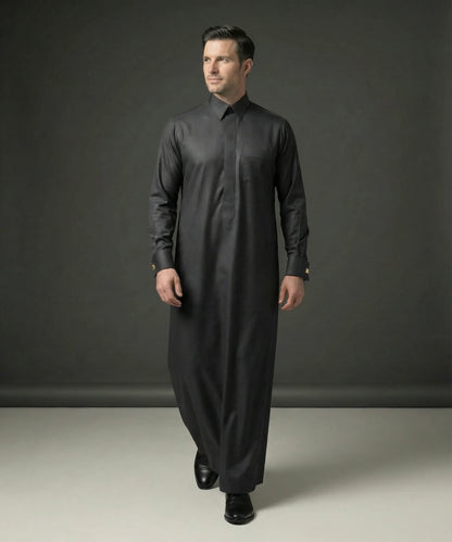 Front walking view of Smoke Black Executive Thobe displaying elegant tailoring, premium fabric, concealed placket design, executive sophistication, and refined Gulf style ideal for weddings, formal gatherings, business occasions, Eid celebrations, and luxury menswear collections. إطلالة أمامية لثوب أسود دخاني فاخر تعكس الرقي والأناقة والفخامة المناسبة للمناسبات الرسمية والاحتفالات الراقية.
