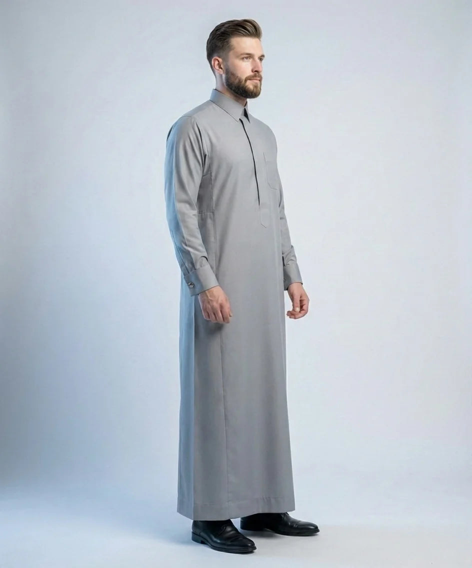 Side profile view of Stone Grey Signature Thobe showcasing elegant structure, premium lightweight fabric, concealed placket, refined craftsmanship, and executive formal styling for contemporary gentlemen. منظر جانبي لثوب رمادي حجري فاخر يبرز التفاصيل الدقيقة والقصة الراقية والتصميم المناسب للمناسبات الرسمية والاجتماعات المهمة.