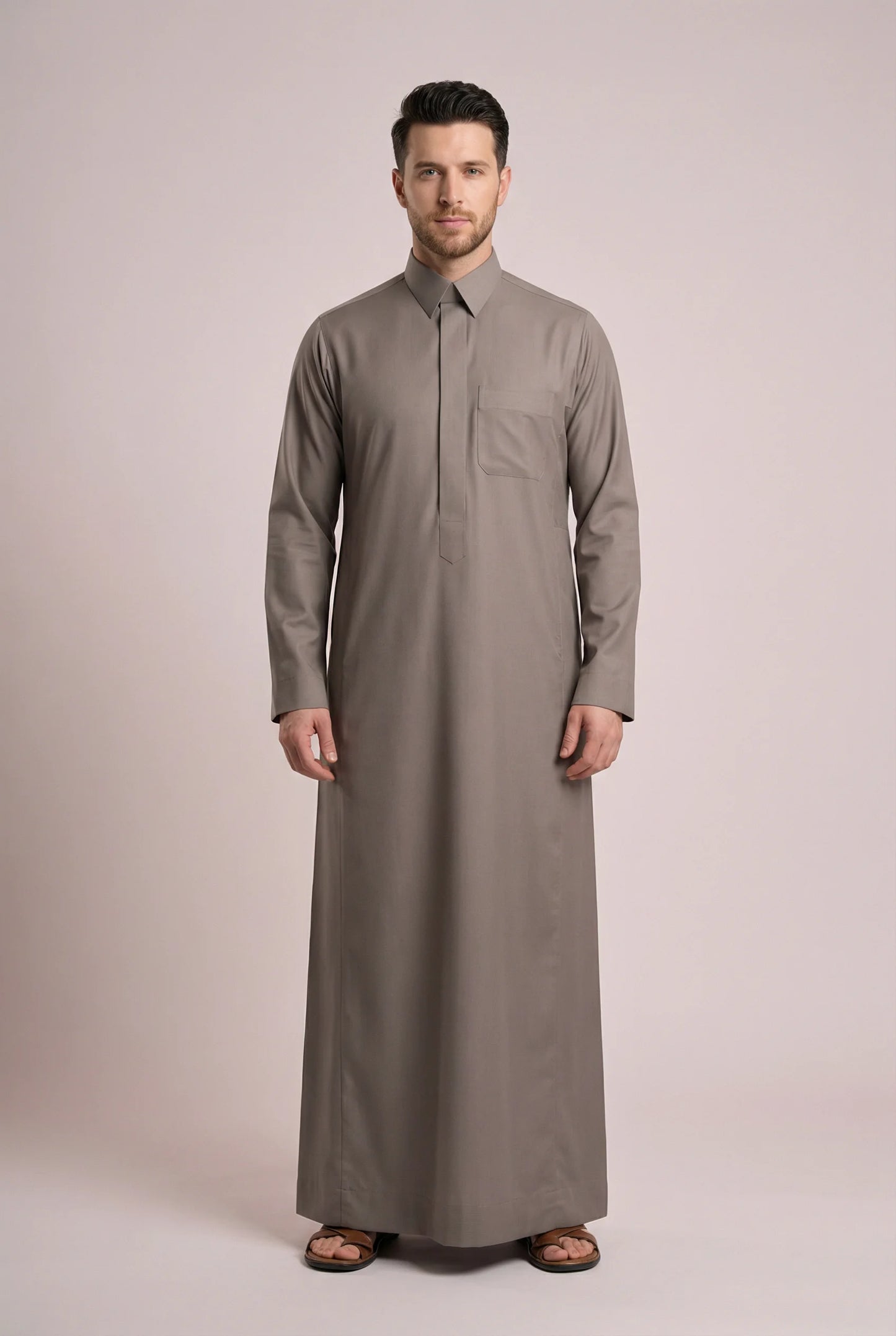 Front view of Warm Grey Everyday Thobe featuring executive tailoring, concealed placket closure, chest pocket detail, structured collar, and premium warm grey fabric. Saudi thobe for men, luxury Islamic clothing, premium jubba, ثوب سعودي رجالي, ثوب رسمي فاخر, جلابية رجالية كلاسيكية, دشداشة رجالية حديثة, elegant modest fashion ideal for Jummah prayer, Eid celebrations, weddings, business meetings, and refined daily wear.