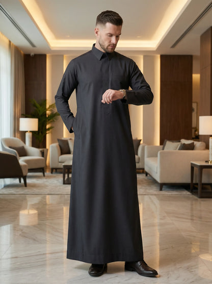 Carbon Black Executive Thobe styled in a luxury interior setting, showcasing confidence, sophistication, and contemporary elegance. Premium Saudi thobe, luxury men's jubba, Islamic menswear, ثوب كربوني أسود فاخر للرجال, ثوب سعودي أنيق, ثوب رجالي رسمي, جلابية رجالية راقية, دشداشة رجالية فاخرة, ملابس إسلامية رجالية, premium modest fashion ideal for professionals, Ramadan, Eid, prayer, family gatherings, and elevated everyday wear.