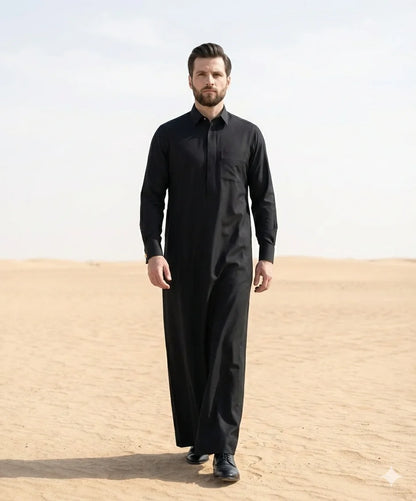 Deep Black Luxury Thobe styled in a premium Gulf-inspired desert setting, showcasing exceptional craftsmanship, timeless elegance, royal sophistication, and distinguished formal wear for modern gentlemen seeking luxury, prestige, and authentic Gulf fashion. ثوب أسود فاخر بإطلالة مستوحاة من الأجواء الخليجية الراقية يجمع بين الفخامة الملكية والأناقة العصرية للمناسبات الخاصة والرسمية.