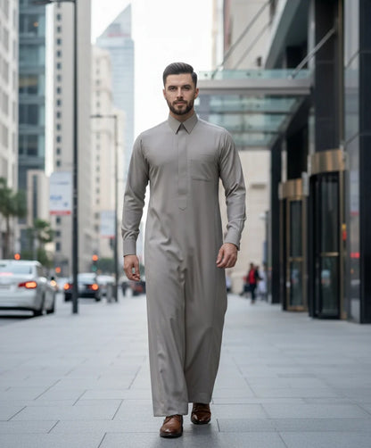 Executive Sand Grey Thobe styled in a modern urban business environment, showcasing exceptional craftsmanship, refined elegance, premium comfort, and sophisticated Gulf fashion for contemporary gentlemen seeking luxury, prestige, and executive formal wear. ثوب رمادي رملي فاخر بإطلالة عصرية في بيئة أعمال راقية تجمع بين الأناقة الحديثة والفخامة الخليجية للمناسبات الرسمية والعملية.