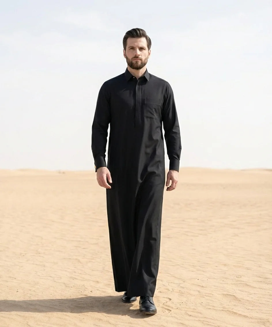 Jet Black Executive Thobe styled in a luxury desert-inspired Gulf setting, combining executive authority, premium craftsmanship, formal sophistication, and timeless elegance for gentlemen seeking prestige, confidence, and distinguished style. ثوب أسود فاحم فاخر بإطلالة مستوحاة من البيئة الخليجية الراقية يجمع بين القوة والفخامة والأناقة التنفيذية للرجل الذي يقدّر الجودة والتميز.