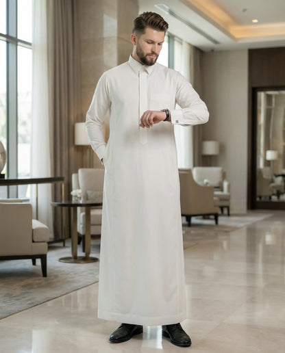 Pearl White Luxury Thobe styled in an elegant executive interior setting, showcasing exceptional craftsmanship, timeless sophistication, premium comfort, and distinguished Gulf fashion for modern gentlemen seeking luxury, prestige, and refined formal wear. ثوب أبيض لؤلؤي فاخر بإطلالة راقية داخل بيئة تنفيذية فاخرة تجمع بين الأناقة العصرية والفخامة الخليجية للمناسبات الخاصة والرسمية.