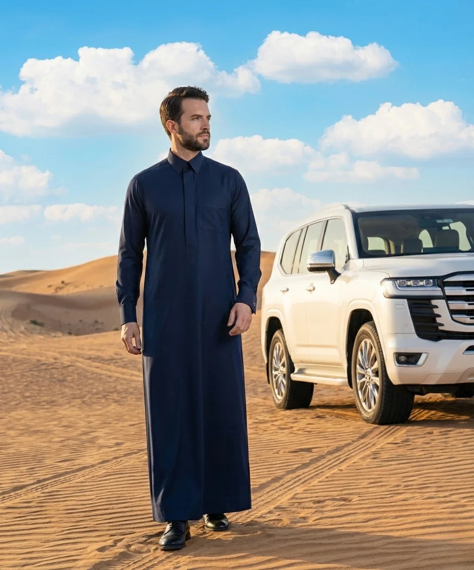 Royal Midnight Formal Thobe styled in a luxury desert setting beside a premium SUV, showcasing confidence, prestige, executive elegance, refined Gulf fashion, and timeless sophistication. Designed for weddings, formal celebrations, elite gatherings, and modern gentlemen who appreciate premium craftsmanship and distinguished style. ثوب أزرق ليلي فاخر بإطلالة صحراوية راقية يجمع بين الفخامة الخليجية والأناقة العصرية للمناسبات المميزة والاحتفالات الرسمية.