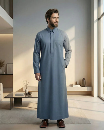 Steel Blue Classic Thobe Modern Everyday Confidence styled in a luxury contemporary interior, showcasing premium Islamic menswear with timeless Arab elegance and sophisticated tailoring. Luxury Saudi thobe, men's designer thobe, premium jubba, ثوب سعودي فاخر للرجال, ثوب أزرق فولاذي, ثوب رجالي أنيق, جلابية رجالية فخمة, دشداشة رجالية راقية, ملابس إسلامية رجالية, ثوب يومي فاخر, modest fashion designed for professionals seeking comfort, confidence, elegance, and versatility throughout Ramadan, Eid, formal gathe