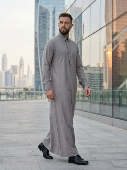 Luxury Stone Grey Signature Thobe by Haybah styled in a modern urban business setting, highlighting premium craftsmanship, breathable comfort, refined elegance, and sophisticated formal fashion for modern gentlemen. ثوب رمادي حجري فاخر بإطلالة عصرية في بيئة أعمال راقية يجمع بين الفخامة والراحة والأناقة ليمنح الرجل حضوراً مميزاً في الاجتماعات والمناسبات الرسمية.